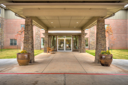 The welcoming entrance of a modern facility, featuring elegant stone details and well-kept landscaping.