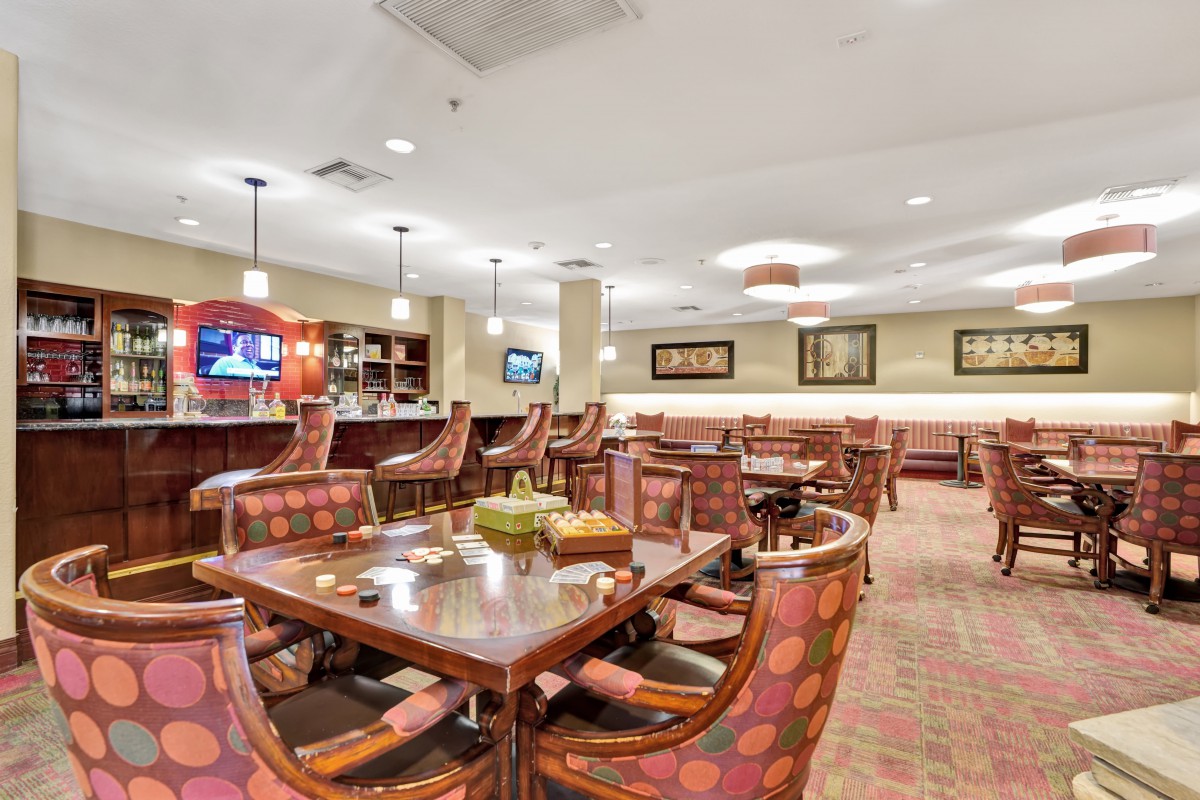 Interior view of a restaurant dining area with tables, chairs, and a bar.