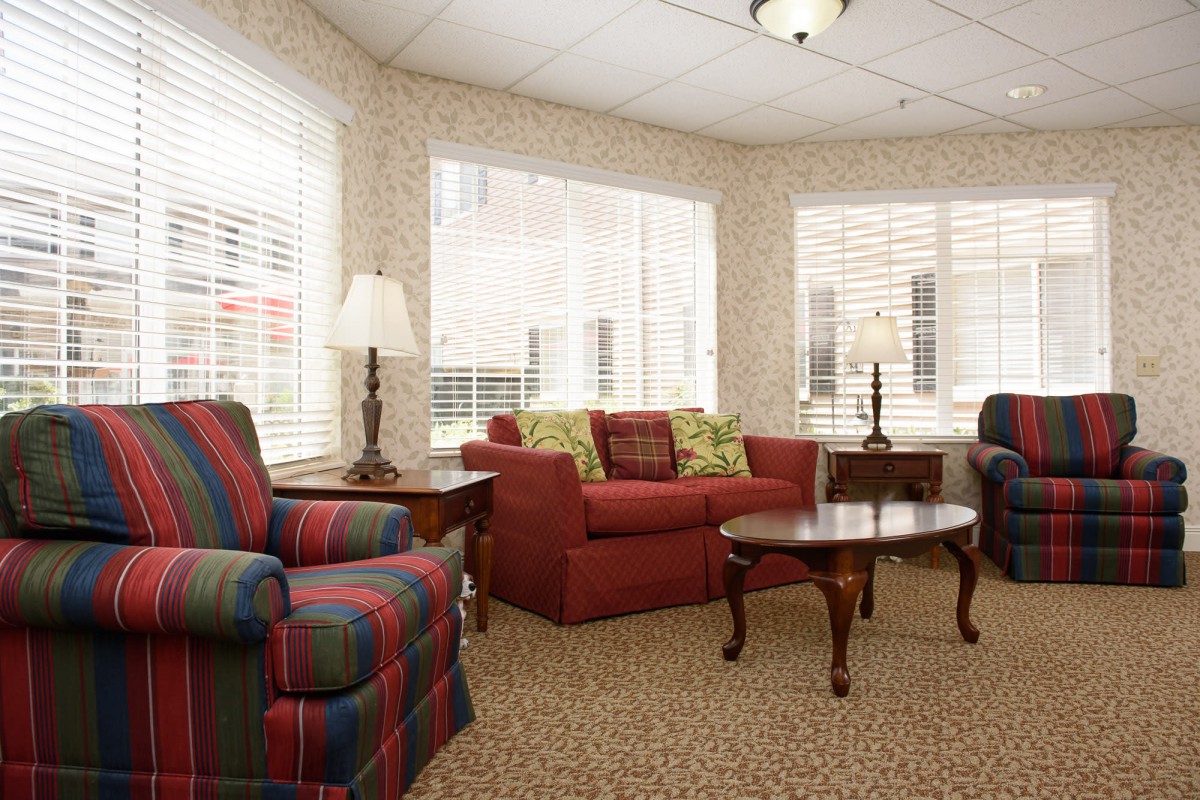 Cozy living room with a red sofa, armchair, coffee table, and large windows.