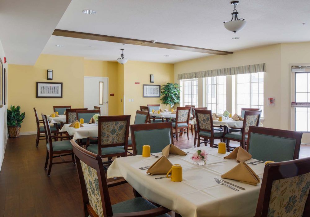 A well-lit dining room with neatly arranged tables and chairs, ready for service.
