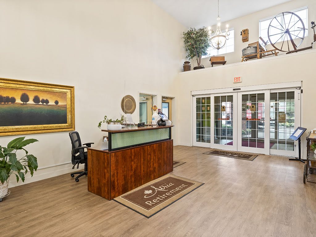 A welcoming reception lobby with a wooden desk, artwork, and ample natural lighting.