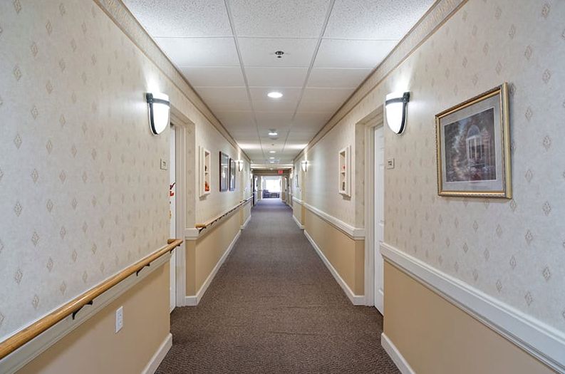A well-lit hallway with carpet, handrails, and framed pictures on the walls.
