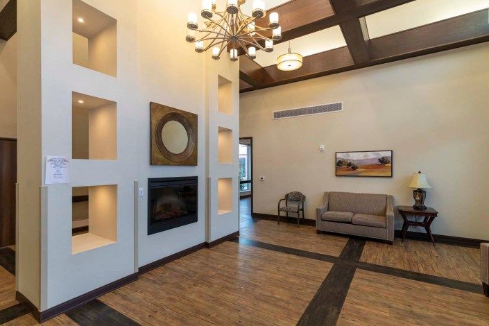 A modern lobby interior featuring a chandelier, comfortable seating area, and artistic wall decor.