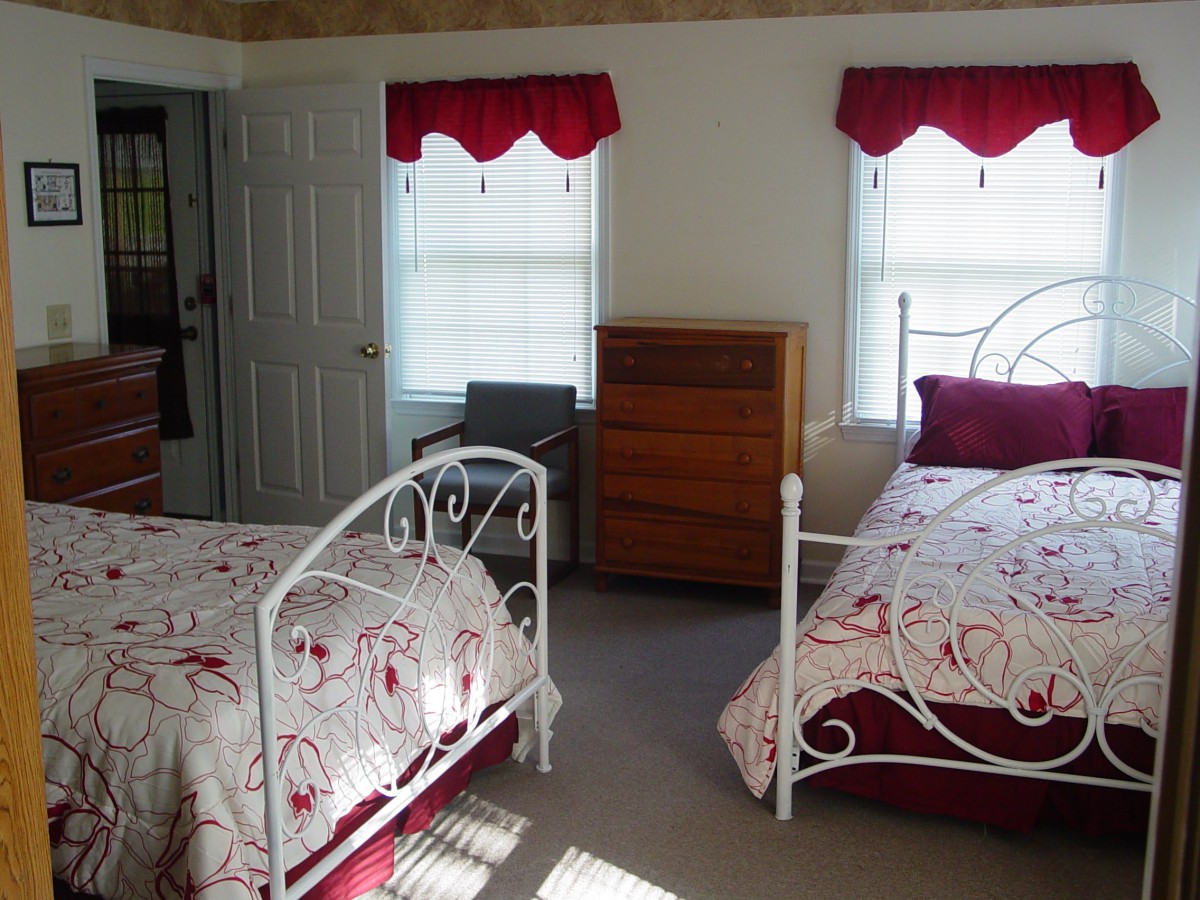 A cozy bedroom featuring two twin beds with floral bedding and red accents.