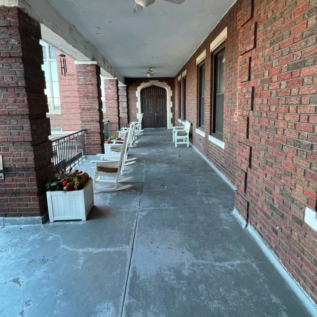 A long corridor with brick walls and chairs lined up alongside the windows.