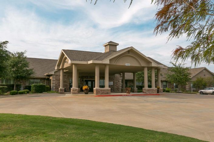 A spacious building with a grand entrance and surrounding greenery.