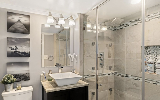 A sleek and modern bathroom featuring a stylish sink, spacious shower enclosure, and elegant lighting.