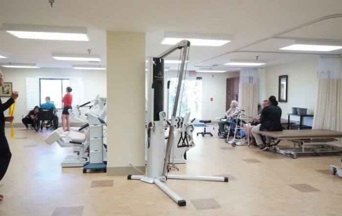 A gym with various exercise equipment and people working out.