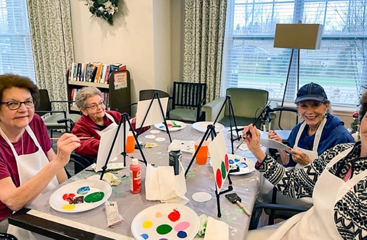 A group of seniors enjoying a painting class together, surrounded by art supplies and canvases.