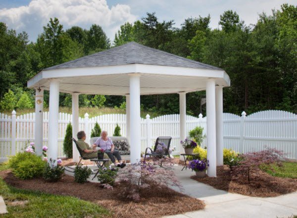 People relaxing under a gazebo in a landscaped garden.