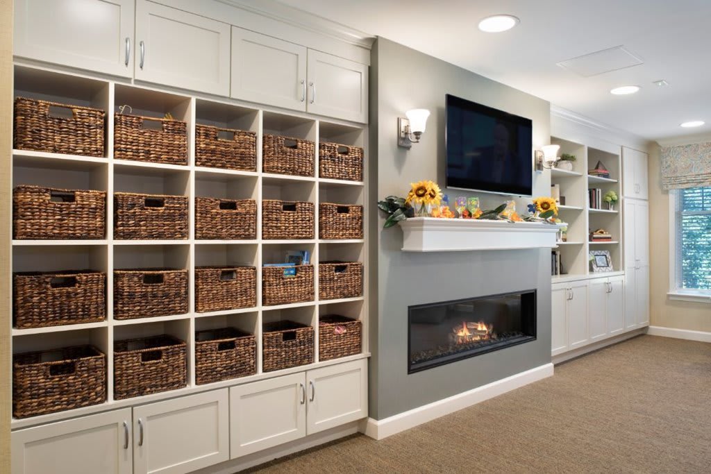A cozy living room with a modern fireplace, built-in shelves, and storage baskets.