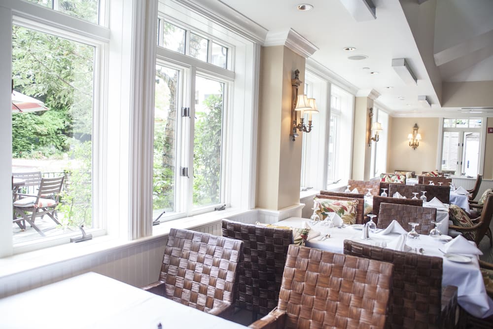 A bright and elegant restaurant dining area with large windows and sophisticated furnishings.