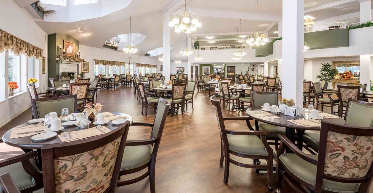 Spacious and elegantly furnished dining area with chandeliers and wooden flooring.