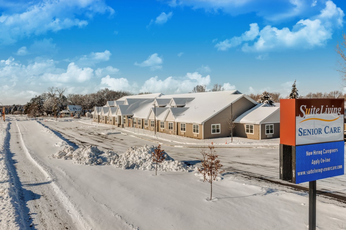 A snowy winter scene with a building and a clear blue sky.