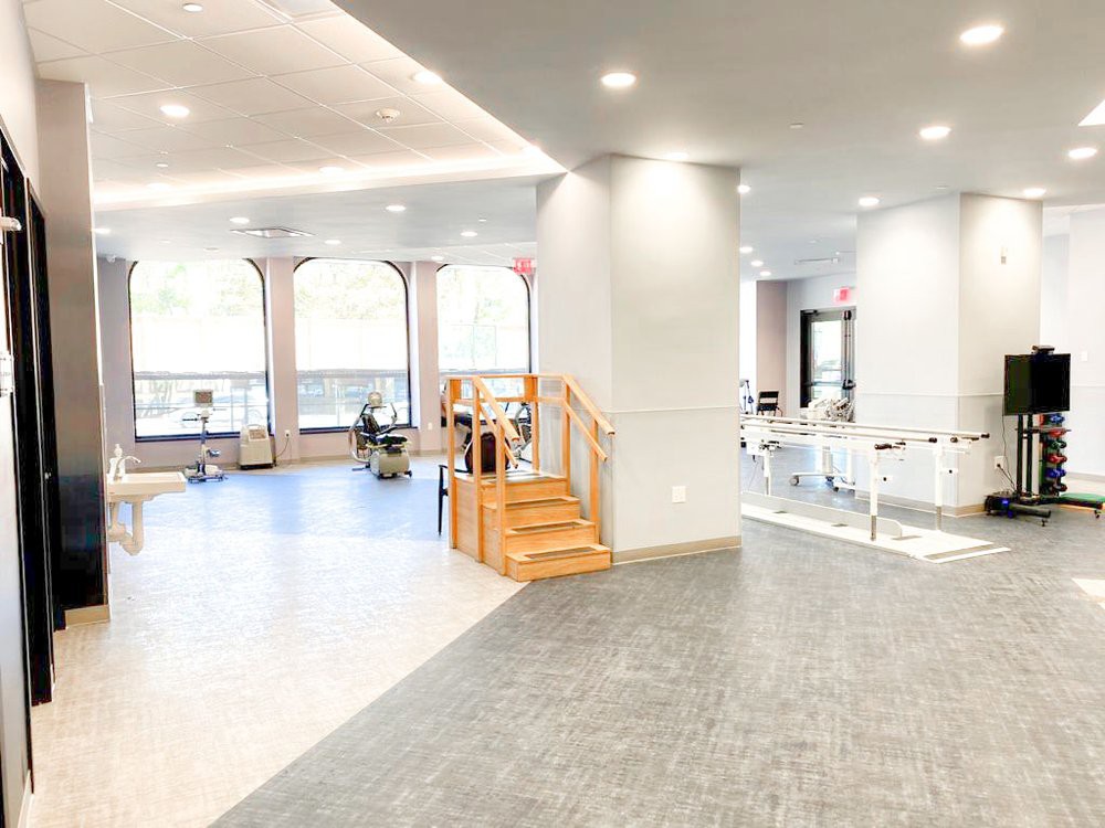 A bright and modern interior with an open layout featuring wooden stairs and plenty of natural light.