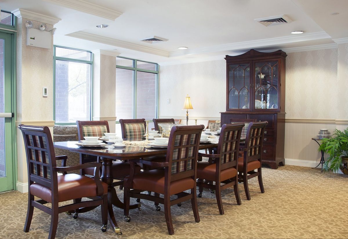 A classic dining room with a long table, surrounded by chairs and a display cabinet.