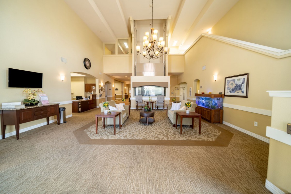 A spacious and modern lobby featuring a central chandelier, comfortable seating, and a fireplace.