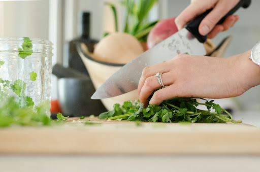 A person chopping fresh herbs in a kitchen setting.