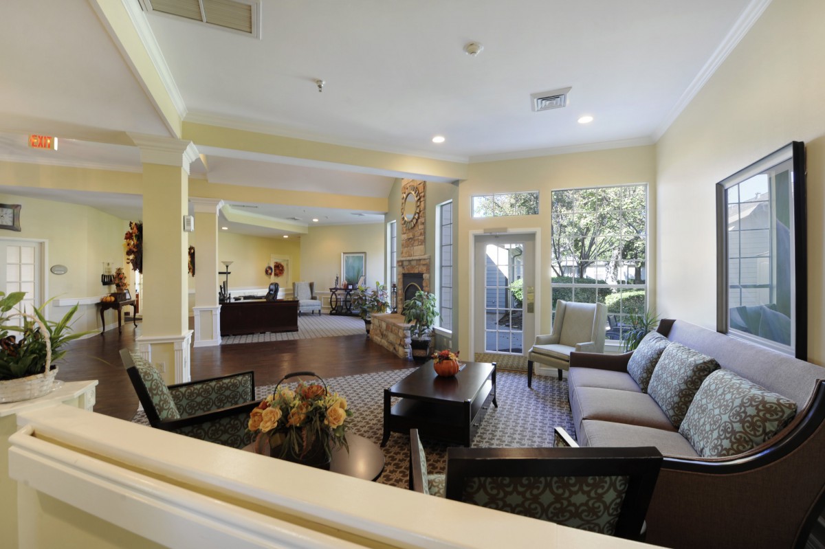A spacious and well-lit living room with comfortable seating and large windows overlooking a garden.