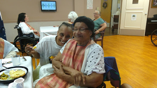 A joyful moment shared between a caregiver and an elderly woman, highlighting the warmth of companionship in a community setting.