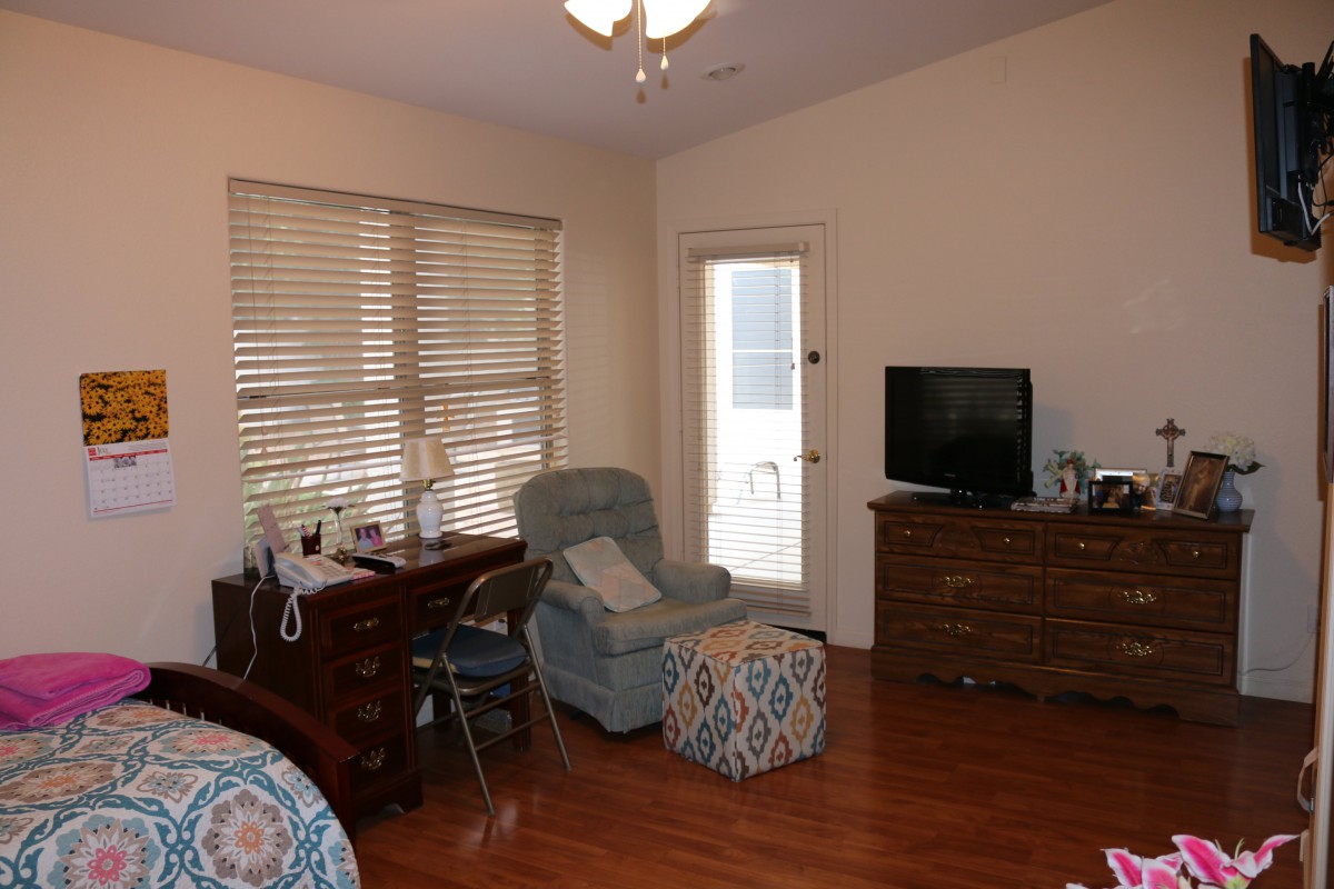 A cozy living room with a chair, desk, and television on a wooden floor.