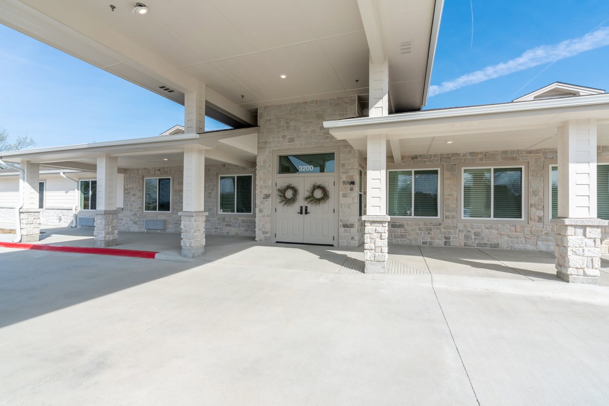 The front entrance of a modern building with a concrete pathway and minimalist design.