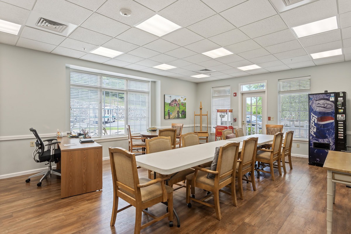 A bright and spacious dining area with tables and chairs, illuminated by natural light through large windows.