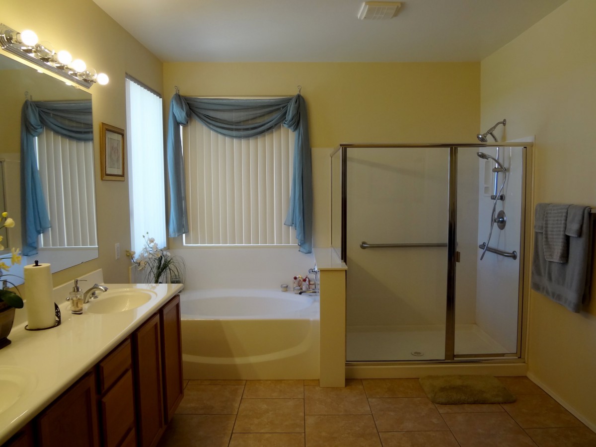 A spacious bathroom featuring a bathtub, shower, and a double sink vanity.