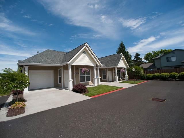 A suburban residential house with a well-maintained driveway under a clear blue sky.