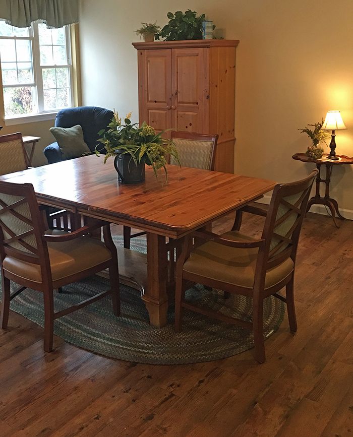 A cozy dining area with a wooden table and chairs, adorned with a plant centerpiece.