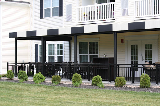 A view of an apartment complex featuring a balcony and well-maintained landscaping.
