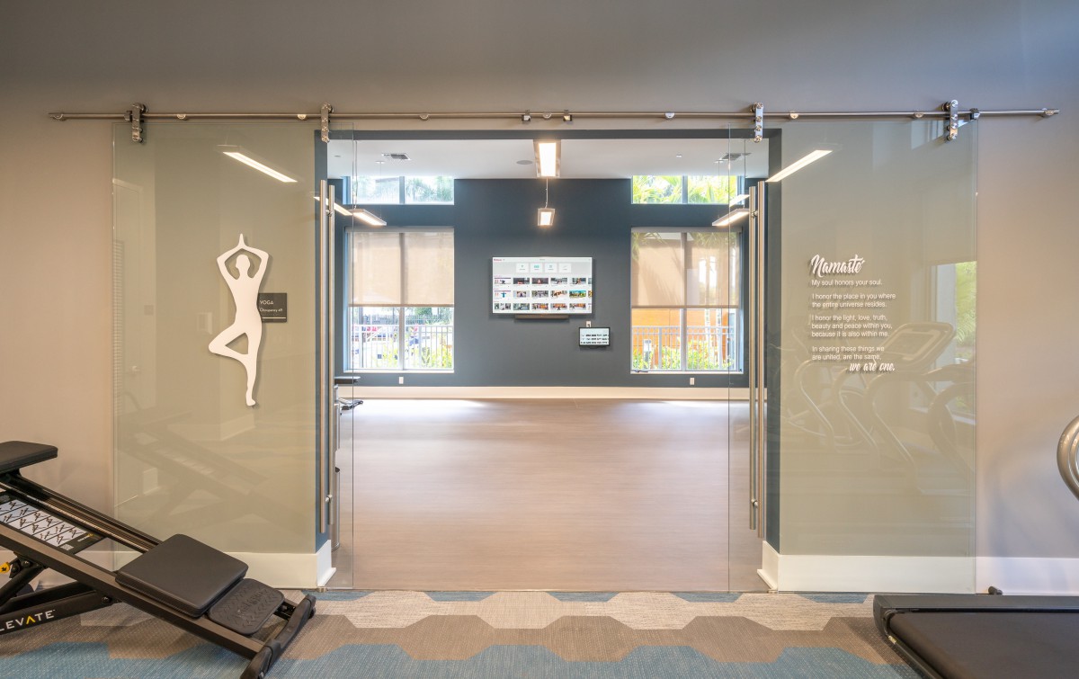 A modern yoga and dance studio with glass doors leading to a spacious, well-lit interior.