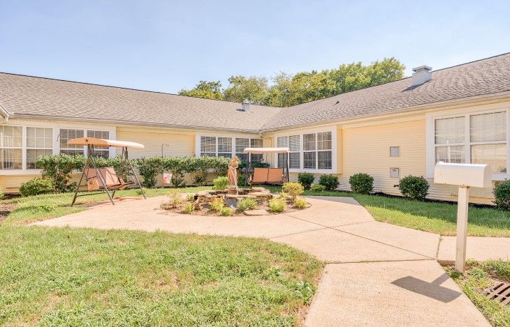 A sunny backyard with a patio and garden, featuring outdoor furniture and well-maintained landscaping.