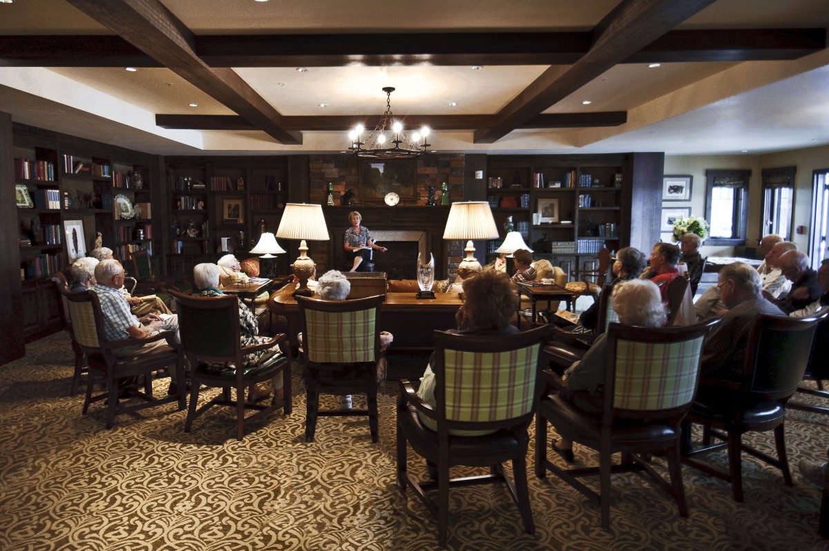 A group of people gathered in a cozy library setting with bookshelves and warm lighting.