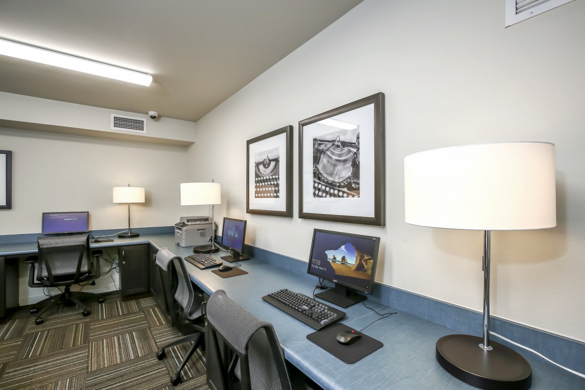 A modern office workspace with computers, desks, and artwork on the walls.