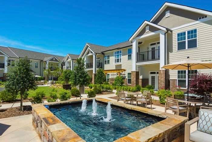 Beautiful apartment complex featuring a landscaped courtyard with a decorative fountain.