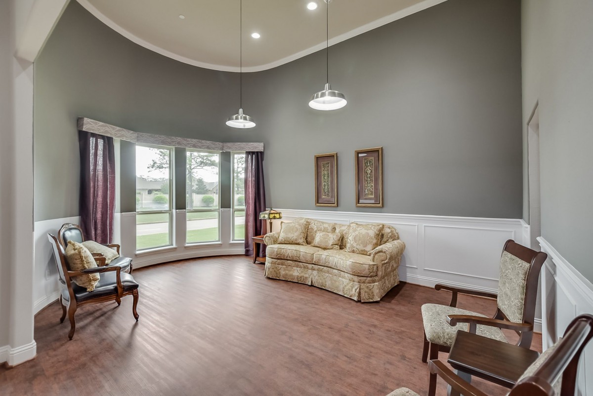 A spacious living room with large windows, elegant furniture, and wood flooring.
