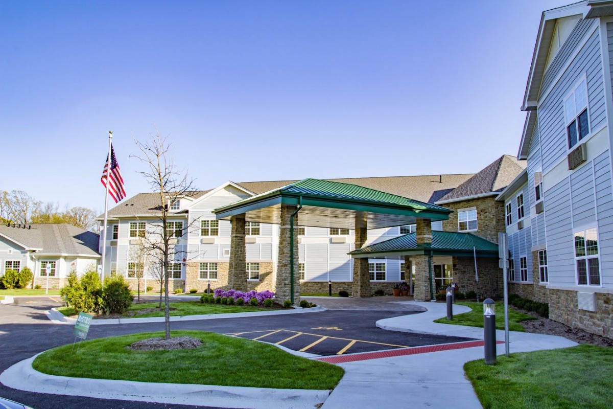 A modern building with a green-roofed entrance and an American flag prominently displayed.