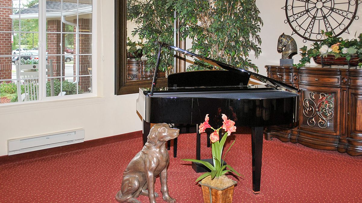A grand piano accompanied by a dog statue and a potted plant in an elegant music room.