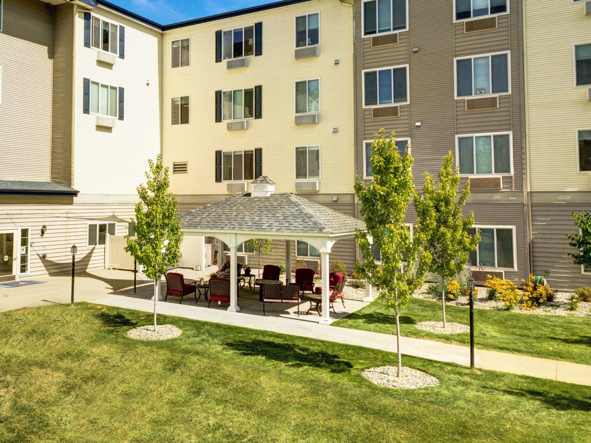 A sunny day view of a residential building with a gazebo and well-maintained lawn.