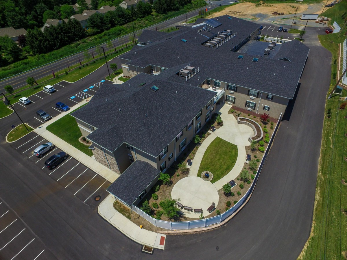 Aerial view of a modern building with surrounding landscaping and parking lot.