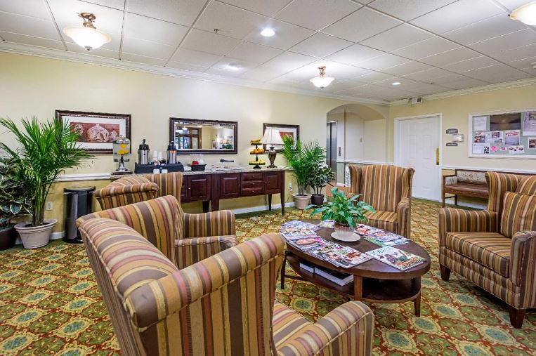 A cozy lobby area featuring striped armchairs, a wooden coffee table, and decorative plants.