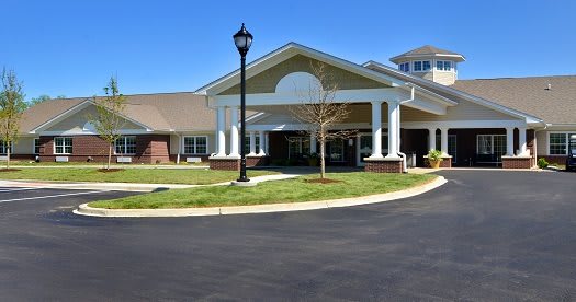 A modern building entrance with landscaping and a clear sky.