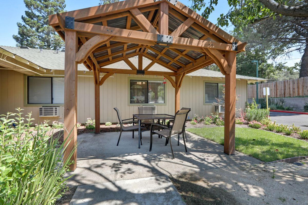 A cozy backyard pergola with a patio set on a sunny day.