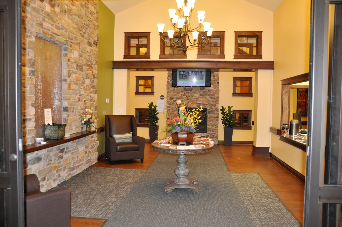A cozy lobby area featuring a stone wall, chandelier lighting, and a central decorative table with floral arrangements.