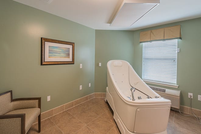 A modern bathroom featuring a sleek bathtub and soothing green walls.
