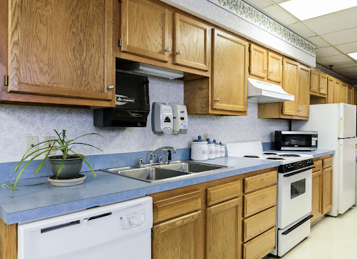 A cozy kitchen featuring wooden cabinets and blue countertops, complete with essential appliances.