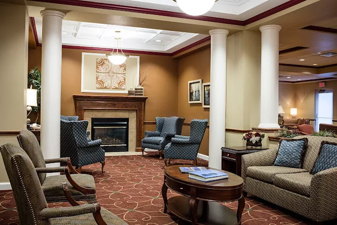 A cozy lobby interior featuring a fireplace, comfortable seating, and elegant columns.