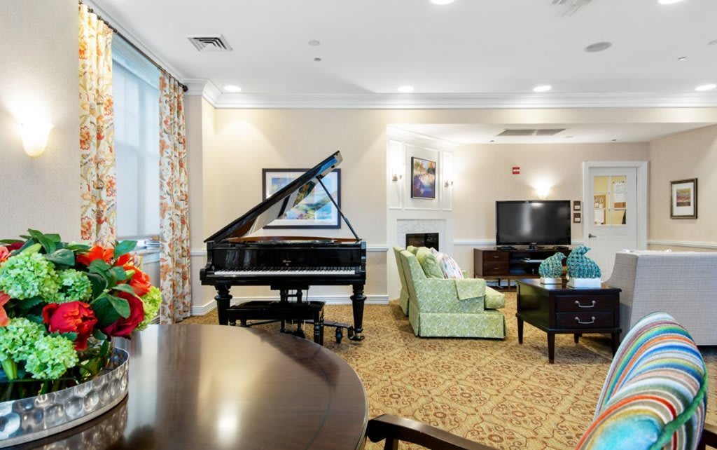A elegantly furnished living room featuring a grand piano, comfortable seating, a large television, and tasteful artwork.