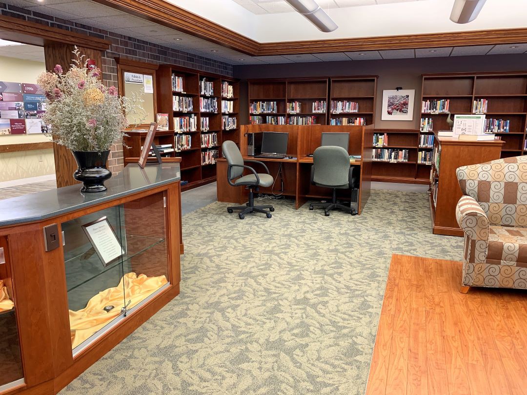 A quiet library space with bookshelves, chairs, and tables for reading.